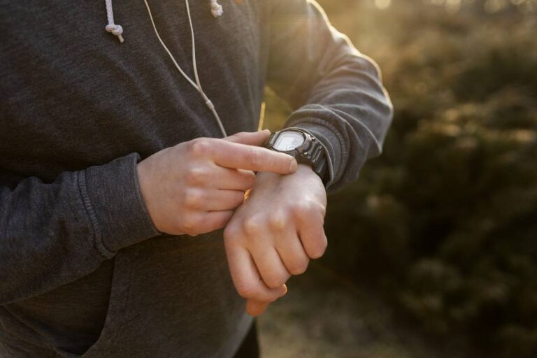 giovane uomo che controlla il suo smartwatch mentre fa esercizio all'aperto