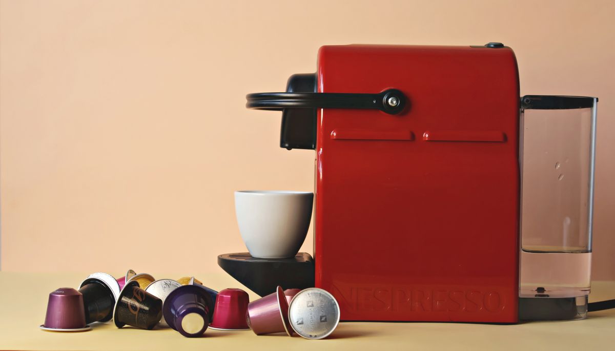 Macchina da caffe a capsule Nespresso rossa con tazza e capsule assortite