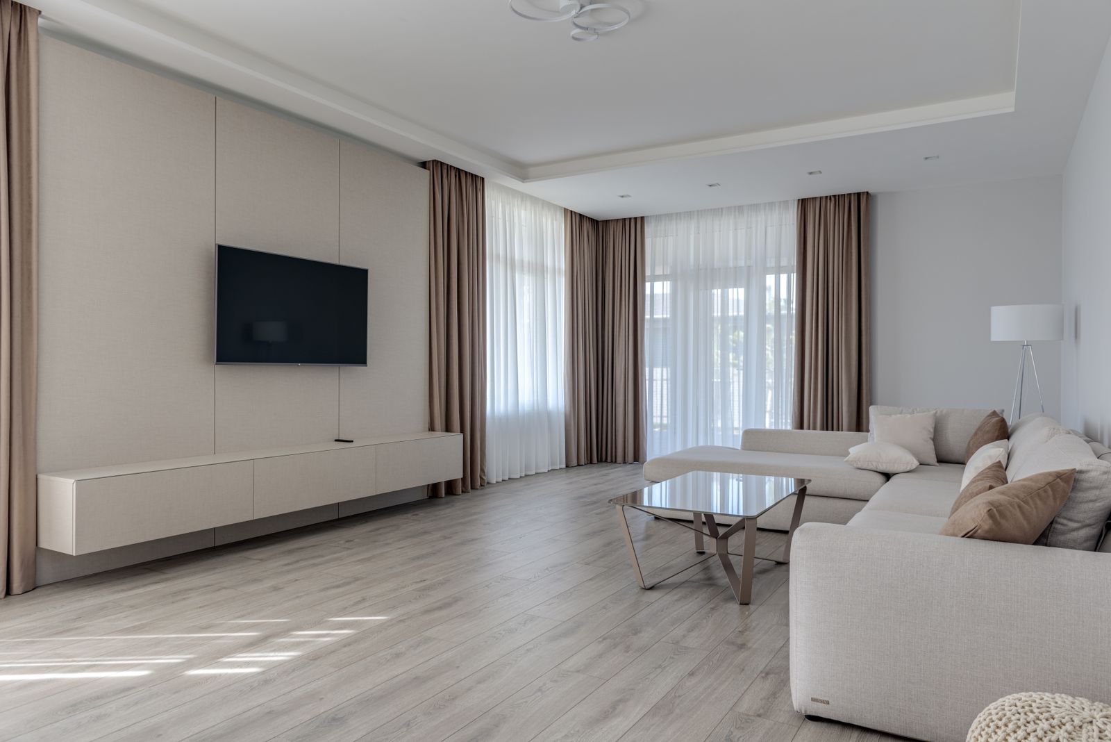 Smart TV 4K da 55 pollici a parete in un soggiorno moderno con grandi finestre