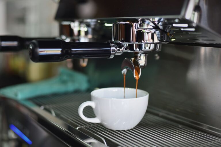Caffè espresso che scende dal braccetto di una macchina in una tazzina bianca