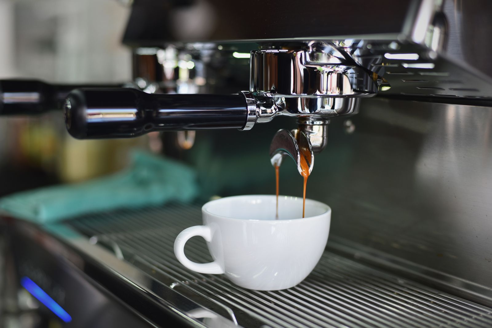 Caffè espresso che scende dal braccetto di una macchina in una tazzina bianca
