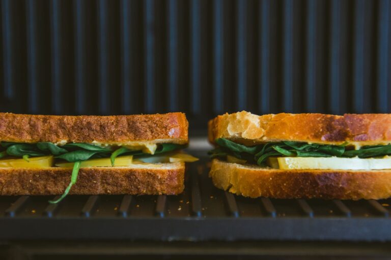 Due toast farciti con formaggio e verdure in cottura su una piastra elettrica rigata